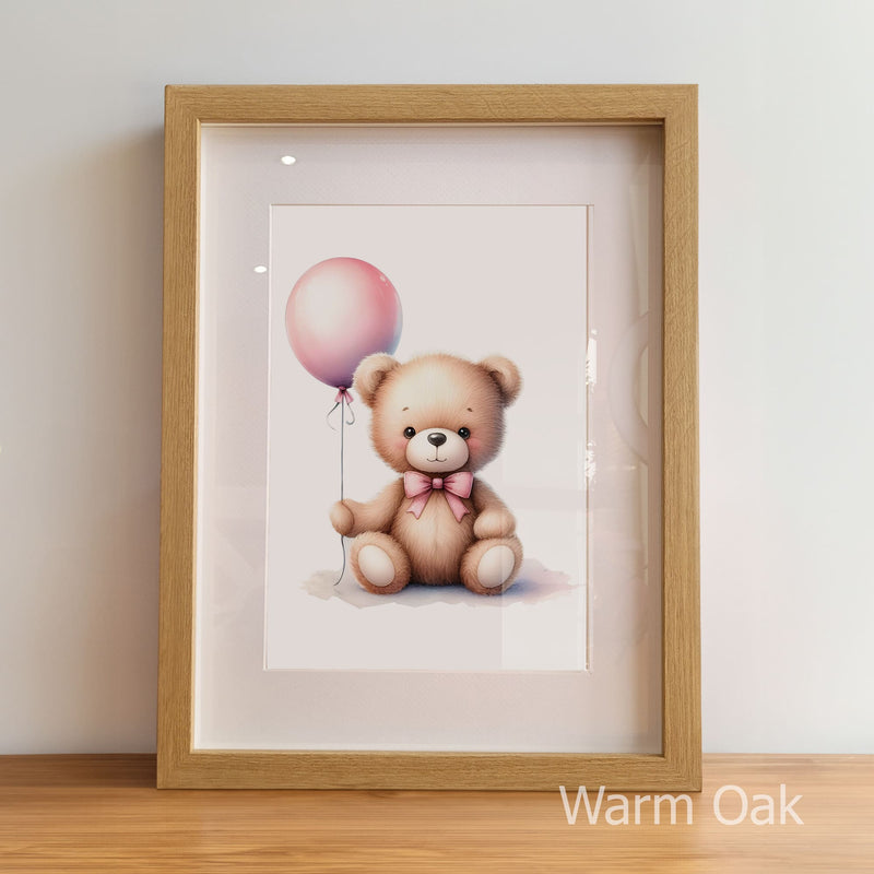 Framed artwork of a teddy bear with a pink balloon inside a warm oak frame.