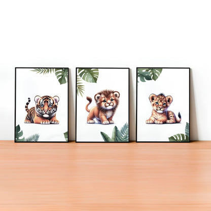 Set of three A4 prints featuring baby big cats - lion cub, tiger cub, and cheetah cub. The animals are depicted in a cartoony, bright style, resembling coloured pencil drawings. Jungle-style leaves adorn the edges of the prints. 