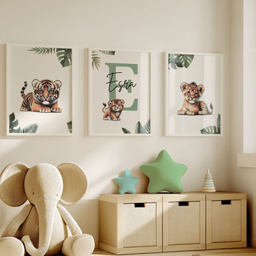 Set of three A4 prints featuring baby big cats - lion cub, tiger cub, and cheetah cub. The animals are depicted in a cartoony, bright style, resembling coloured pencil drawings. Jungle-style leaves adorn the edges of the prints. The middle print features a smaller animal compared to the others, with a large initial letter in the background. A personalised name in black overlays the initial letter.