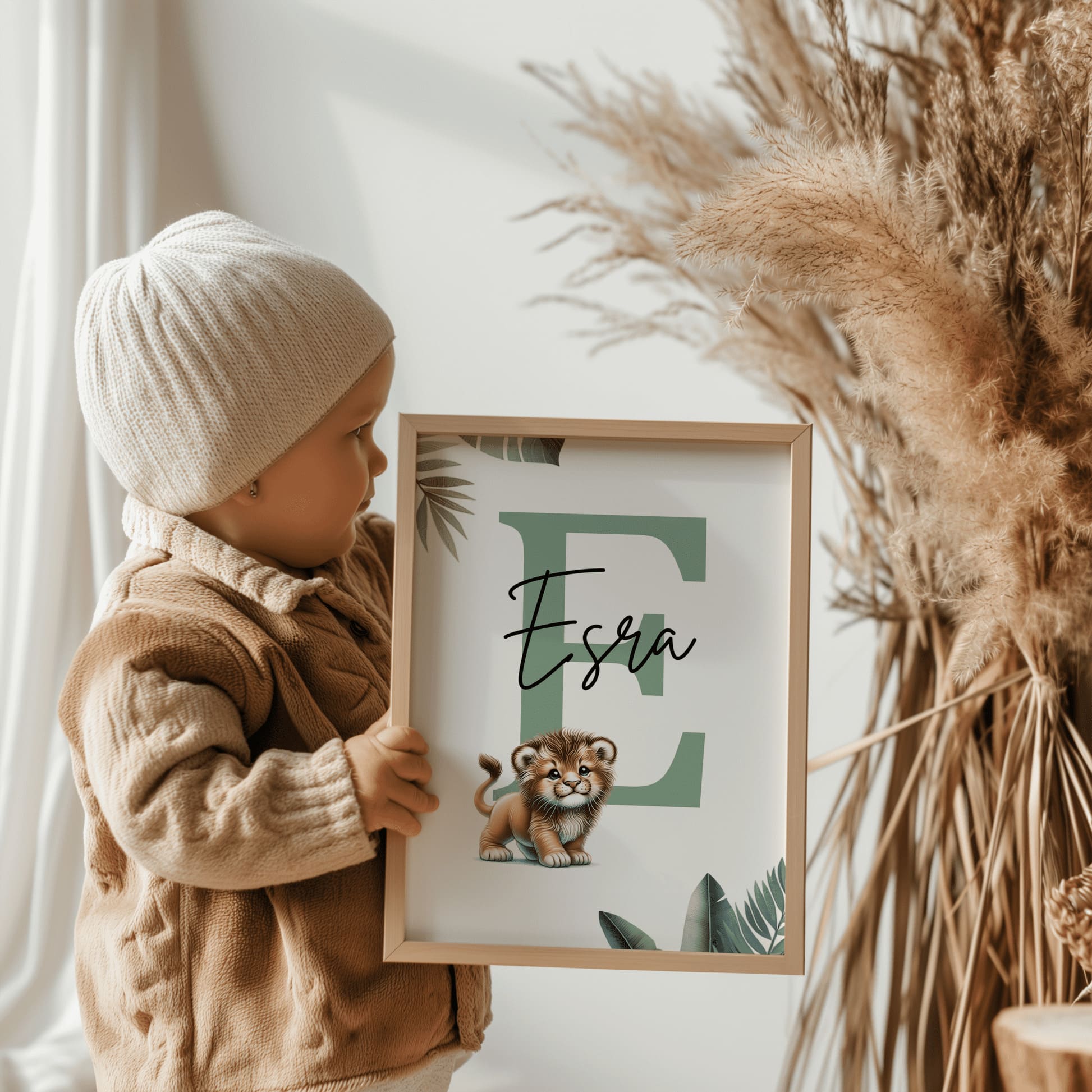 Set of three A4 prints featuring baby big cats - lion cub, tiger cub, and cheetah cub. The animals are depicted in a cartoony, bright style, resembling coloured pencil drawings. Jungle-style leaves adorn the edges of the prints. The middle print features a smaller animal compared to the others, with a large initial letter in the background. A personalised name in black overlays the initial letter.