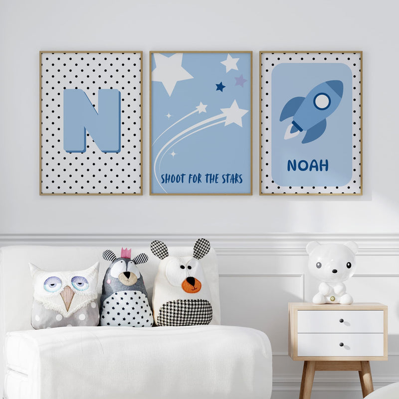 3 Nursery Prints in Blue. One features spotty background with childs initial, one with simple stars on blue background, one with a rocket and childs name