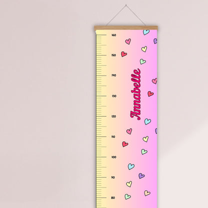 Childs height chart in yellow & pink with colourful love hearts and personalised with your childs name in vibrant pink. Available on black, white or natural hanger