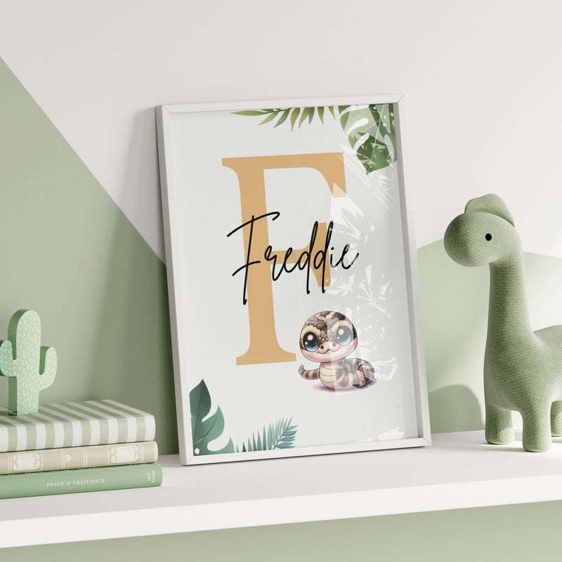 Set of three A4 prints featuring reptiles/amphibians - tree frog, lizard, and snake. The animals are depicted in a cartoony, bright style resembling coloured pencil drawings. Jungle-style leaves decorate the edges of the prints. The middle print features a smaller animal than the others, with a large initial letter in the background. A personalised name in black overlays the initial letter.