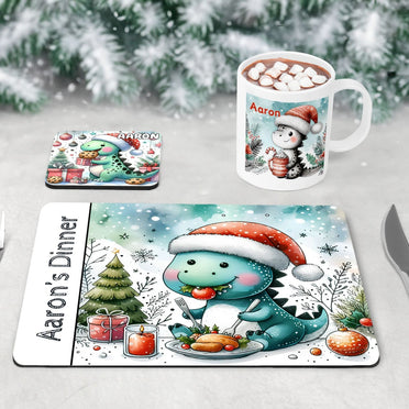 Unique Christmas Dinner Set for Children. Featuring a placemat with a dinosaur eating Christmas dinner, a coaster with a dinosaur eating cookies and a mug with a dinosaur drinking hot chocolate. All personalised with childs name