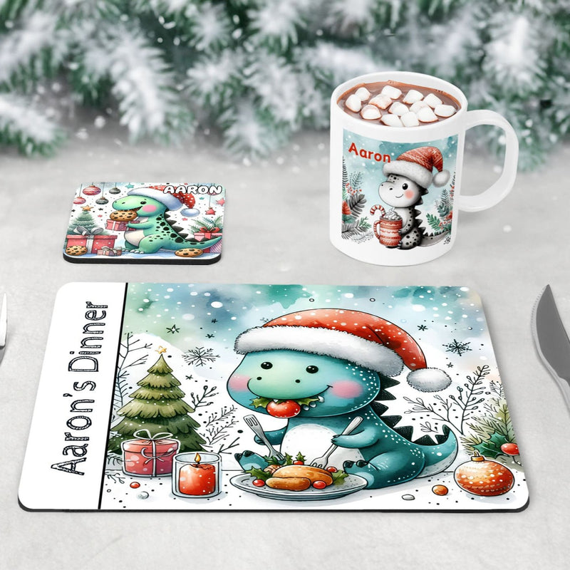 Unique Christmas Dinner Set for Children. Featuring a placemat with a dinosaur eating Christmas dinner, a coaster with a dinosaur eating cookies and a mug with a dinosaur drinking hot chocolate. All personalised with childs name