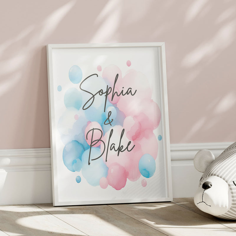 Set of 2 personalised prints for twins' nursery décor. One print features twin giraffes, one wearing a pink bow and the other wearing a blue bow. The prints also include watercolour splashes with children's names in bold black lettering.