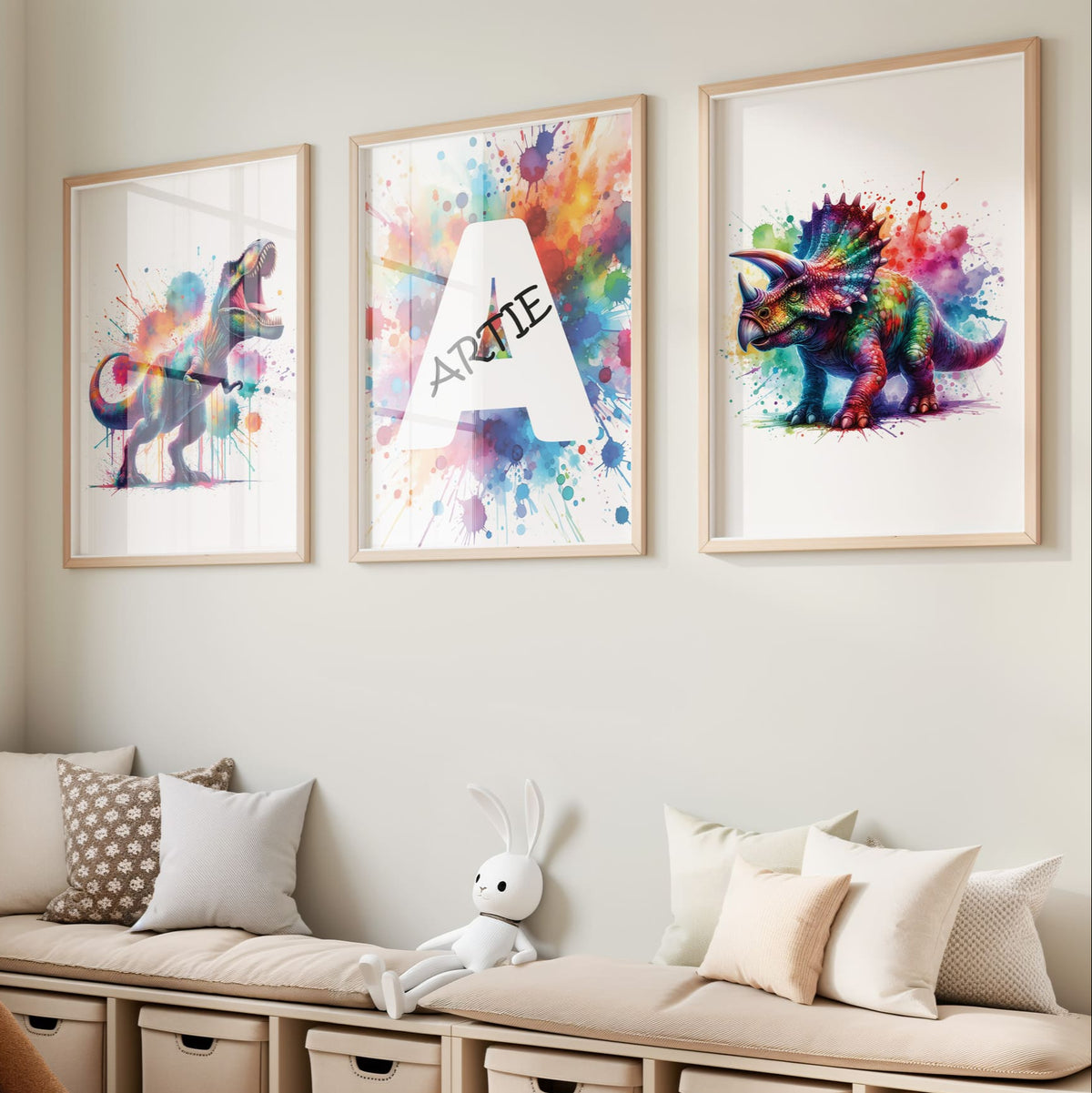 Set of 3 dinosaur prints for children's nursery décor. Two prints feature vibrant, multicoloured dinosaurs in watercolour effects, while the third showcases watercolour splashes with a white initial letter and personalised black name