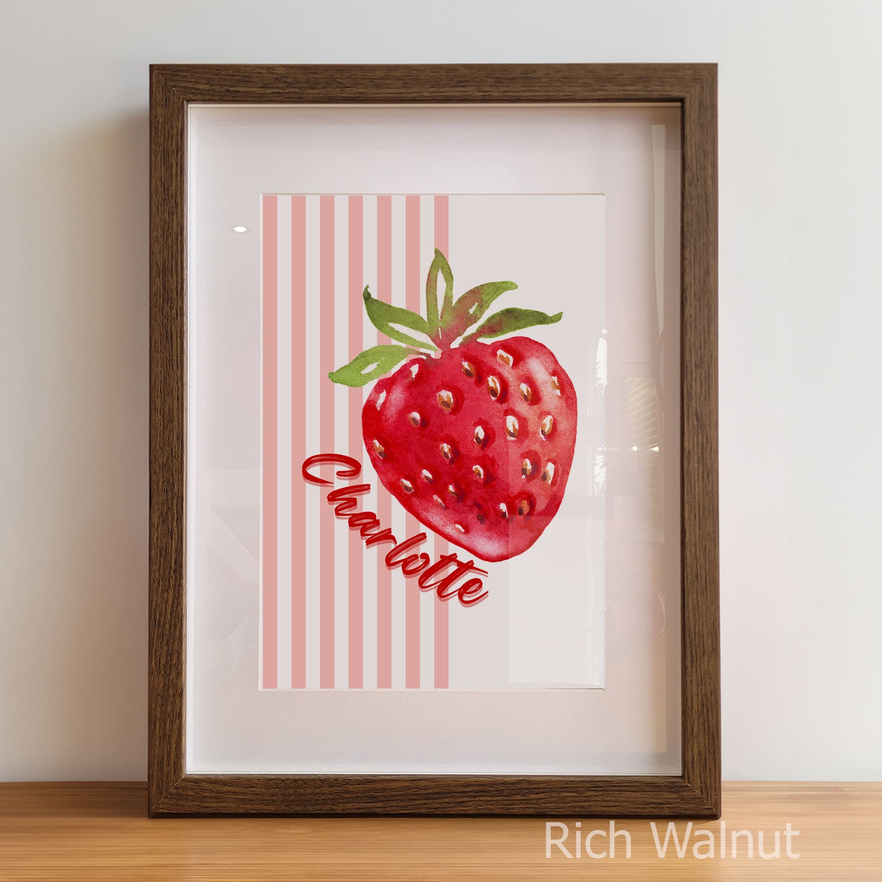 Framed artwork of a red strawberry with green leaves on a white background, featuring the name 'Charlotte'.