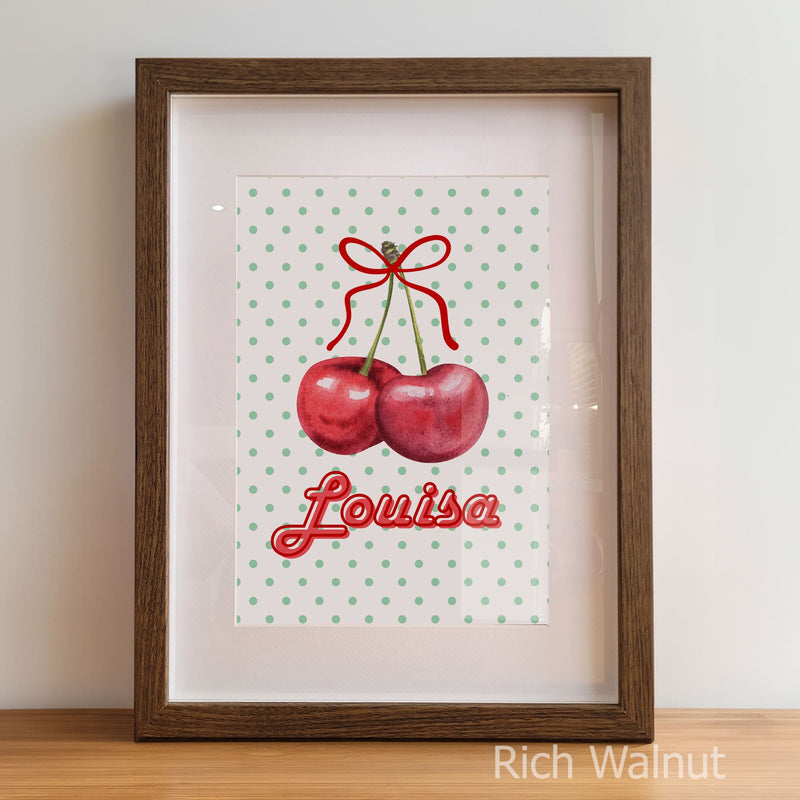 Framed artwork with cherries and the name 'Louisa' on a polka dot background.