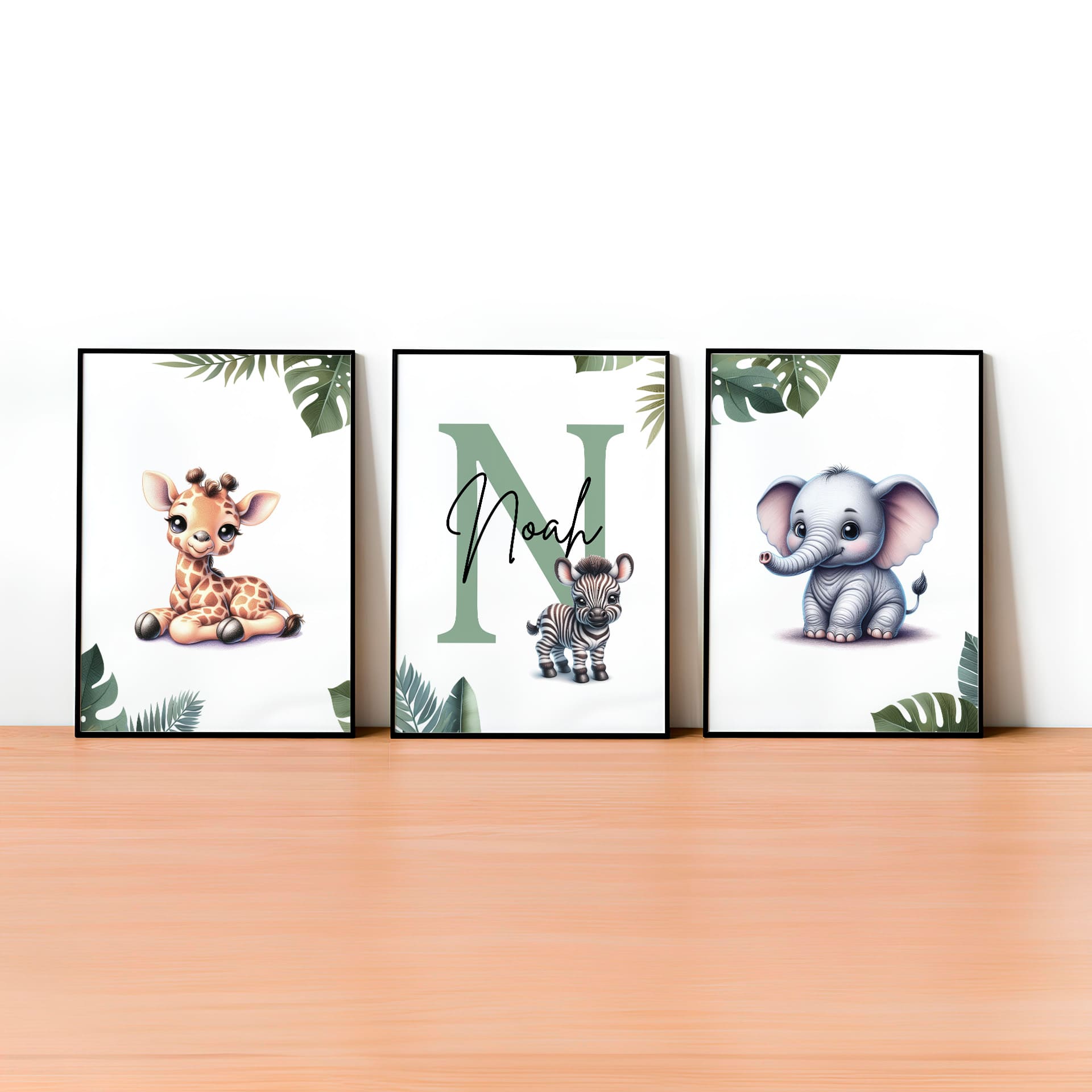Set of  three A4 prints featuring cartoony and brightly illustrated safari animals – an elephant, giraffe, and zebra. The animals are depicted in the style of coloured pencil drawings with jungle-style leaves adorning the edges of the prints. The middle print features a smaller animal compared to the others, with a large initial letter in the background. A personalised name is overlaid in black across the initial letter