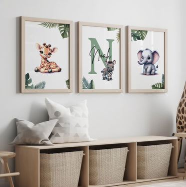 Set of three A4 prints featuring cartoony and brightly illustrated safari animals – an elephant, giraffe, and zebra. The animals are depicted in the style of coloured pencil drawings with jungle-style leaves adorning the edges of the prints. The middle print features a smaller animal compared to the others, with a large initial letter in the background. A personalised name is overlaid in black across the initial letter