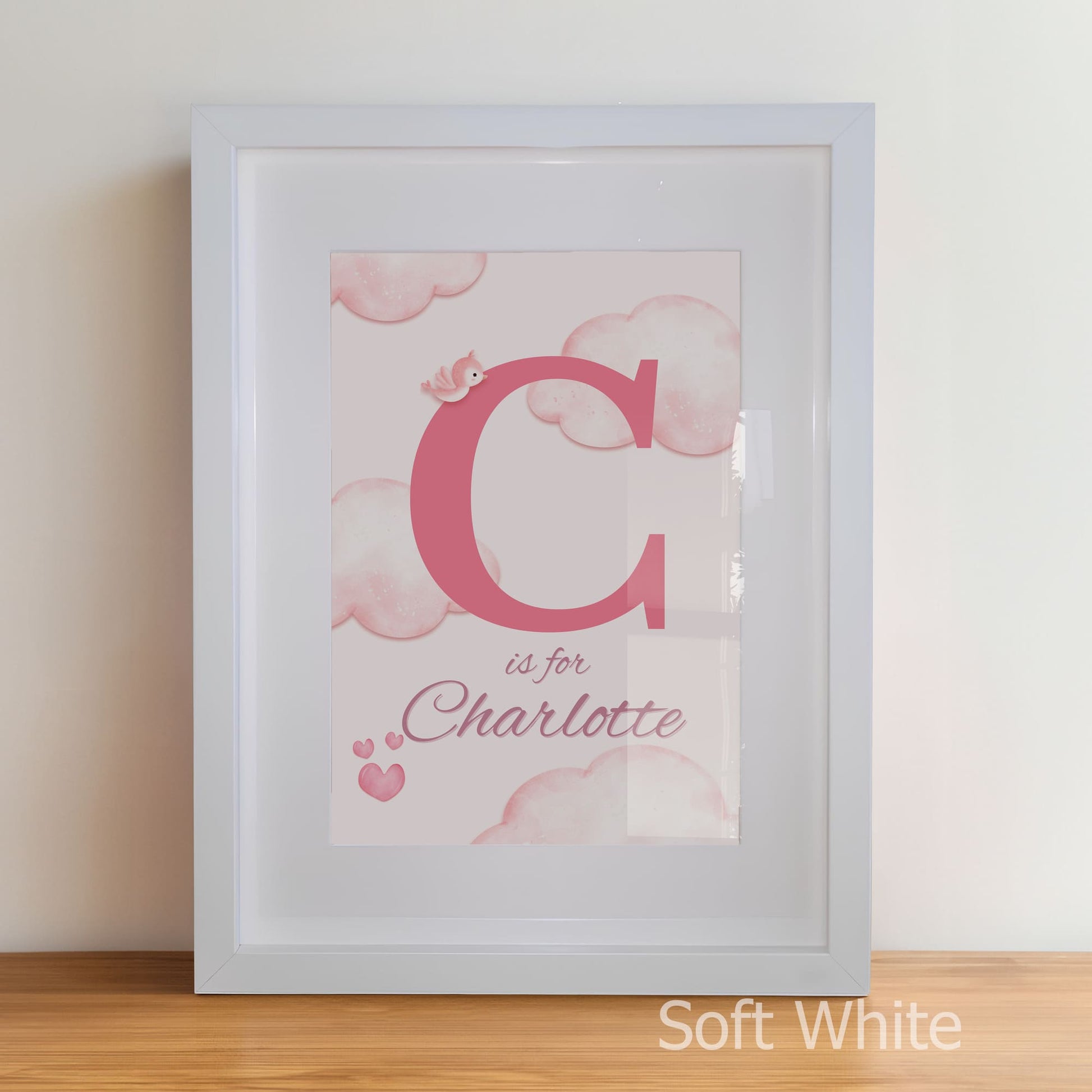 Framed artwork with pink letter 'C' and text 'C is for Charlotte' on a soft white background