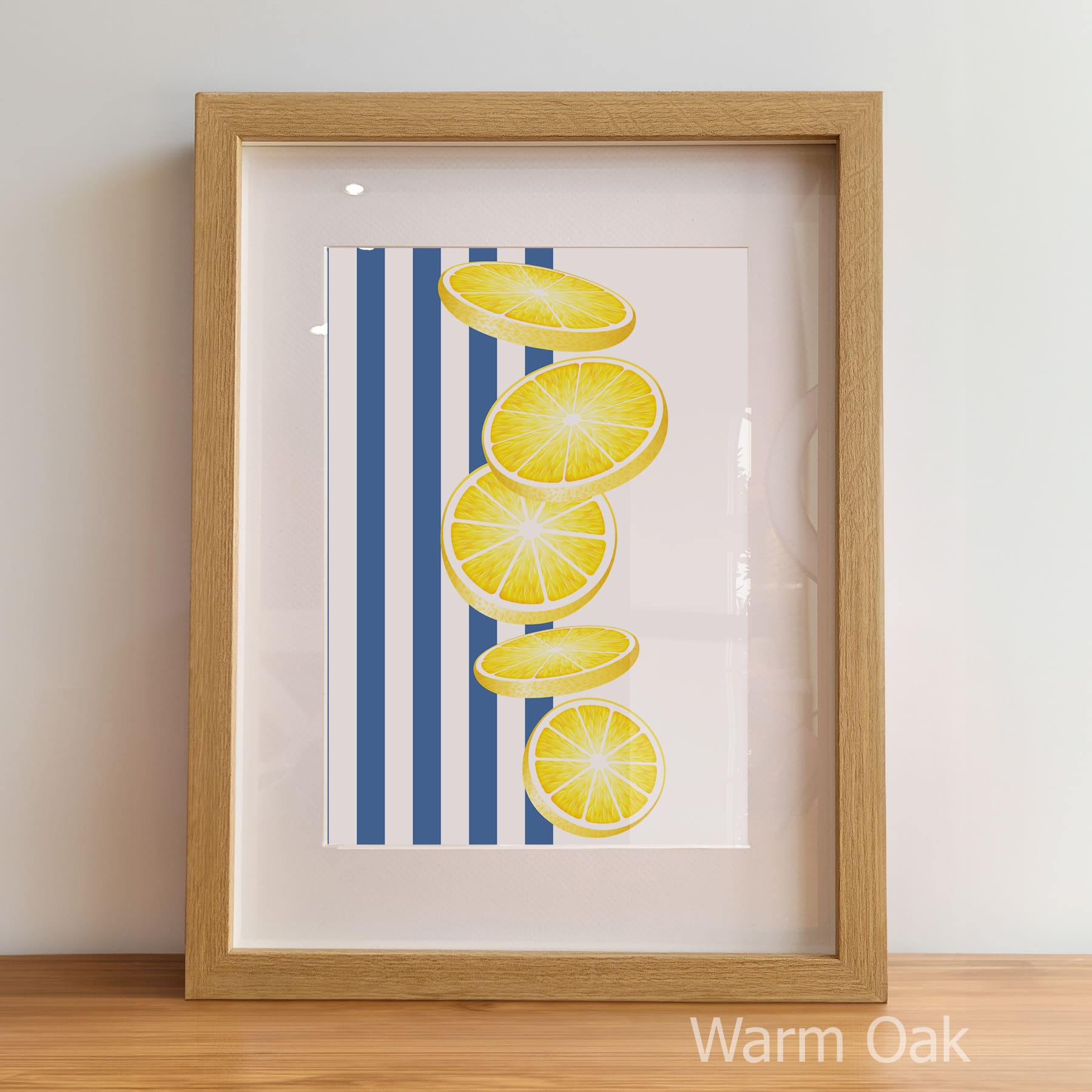 Framed artwork with lemon slices on a striped background, displayed on a wooden surface.