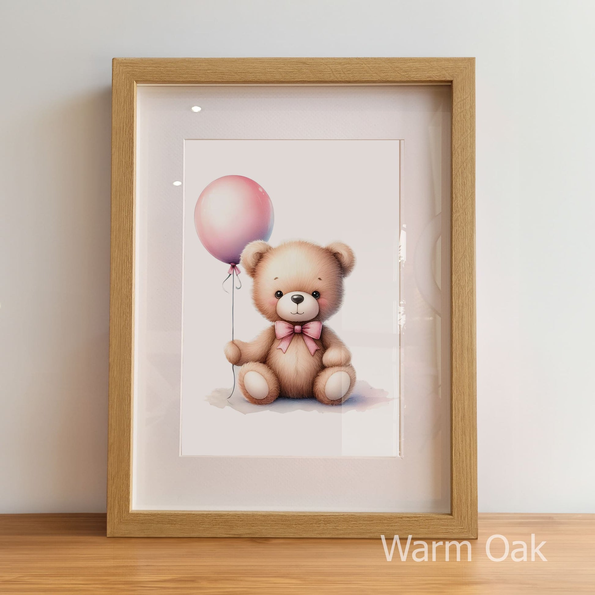 Framed artwork of a teddy bear with a pink balloon inside a warm oak frame.