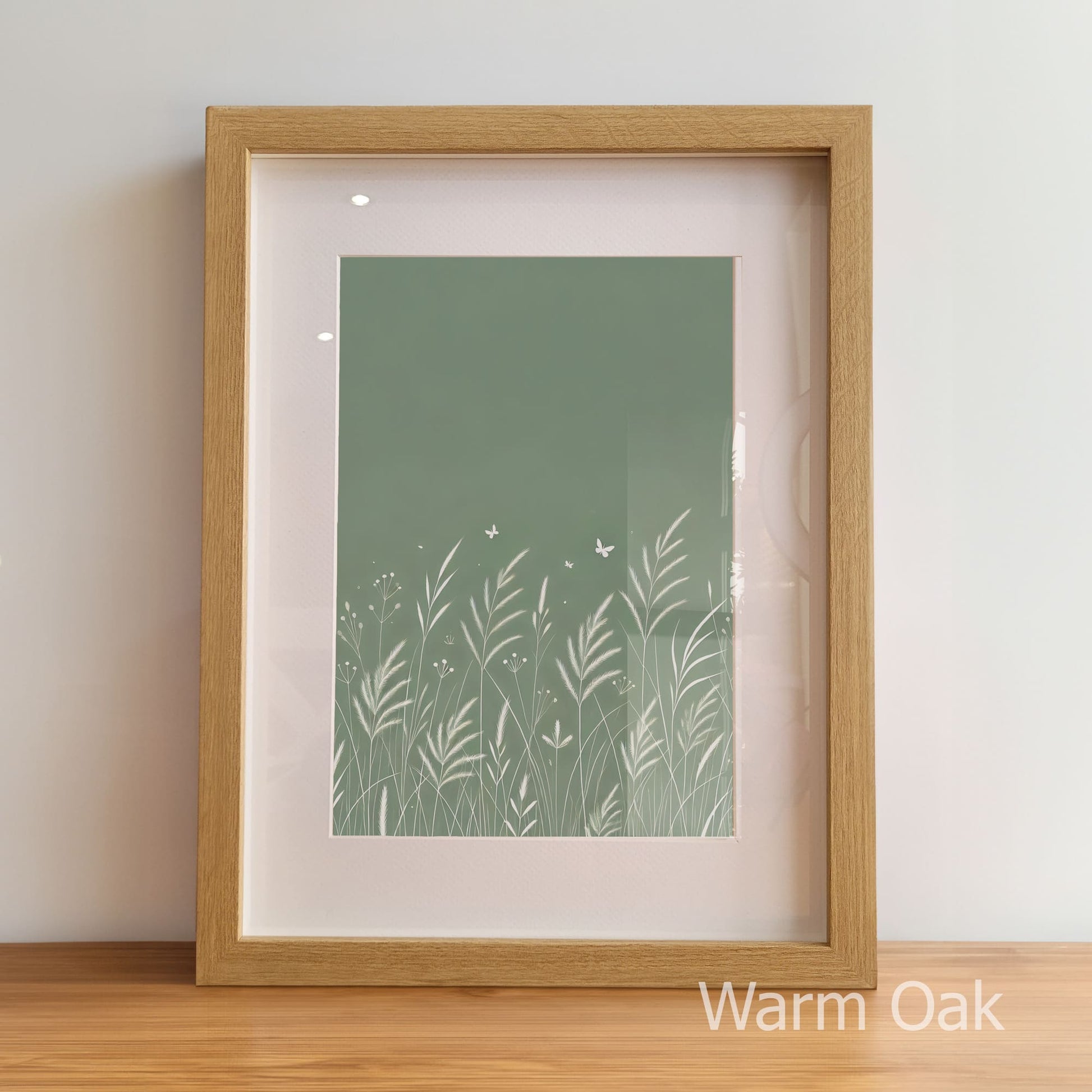 Framed artwork with a green nature-themed print inside, on a wooden floor.