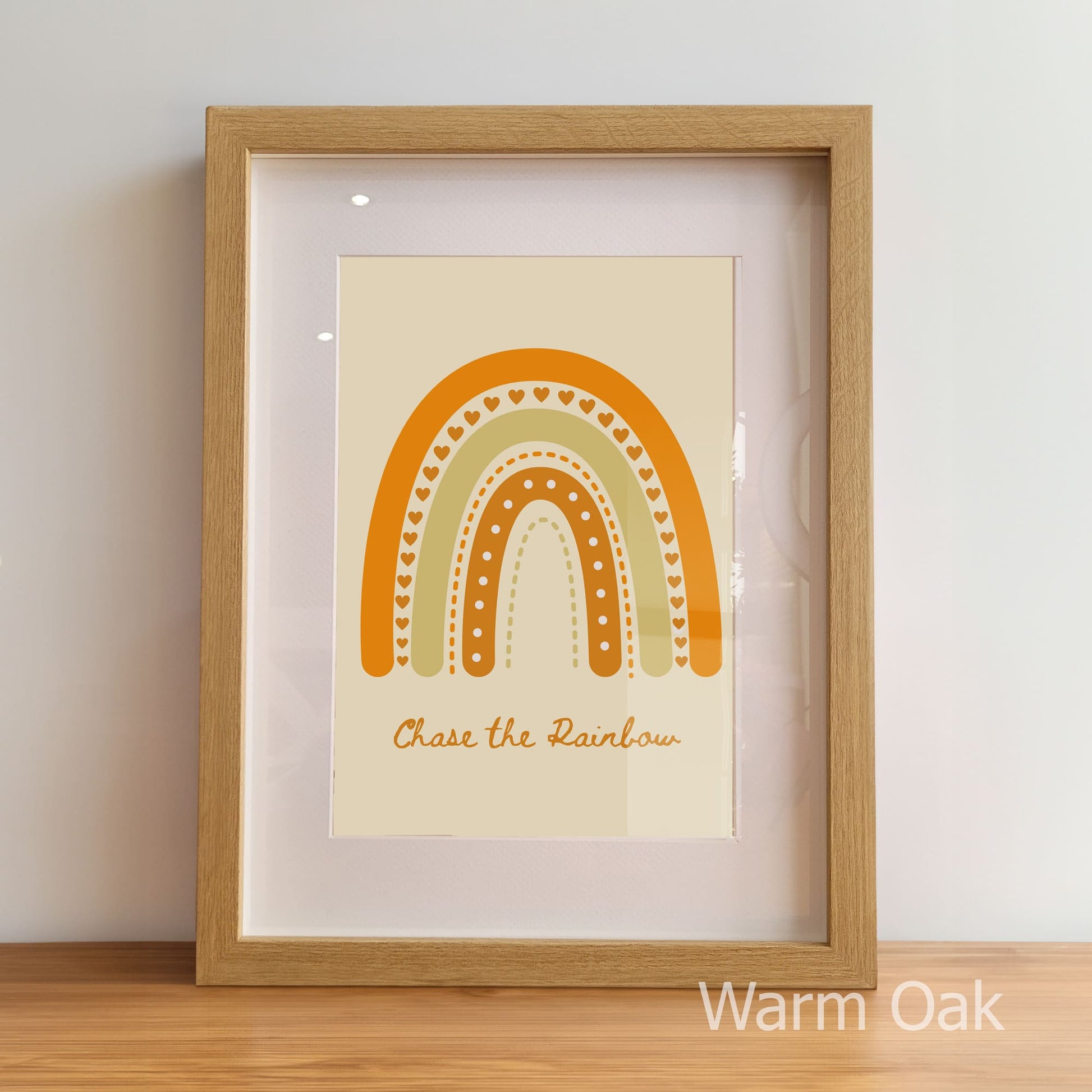 Framed print with a rainbow design and text 'Chase the Rainbow' on a beige background, in a warm oak frame.