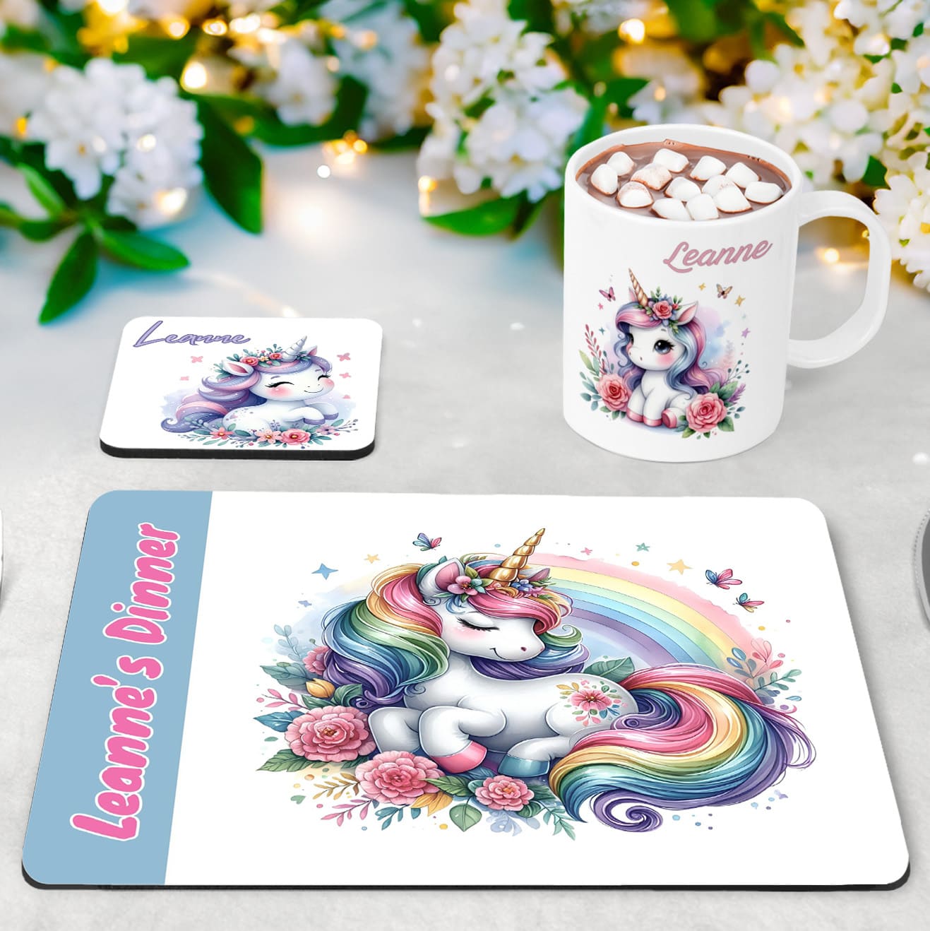 Whimsical flowery unicorn designs in lilacs, baby blue and pinks on a white placemat, mug and coaster set. Personalised with your childs name