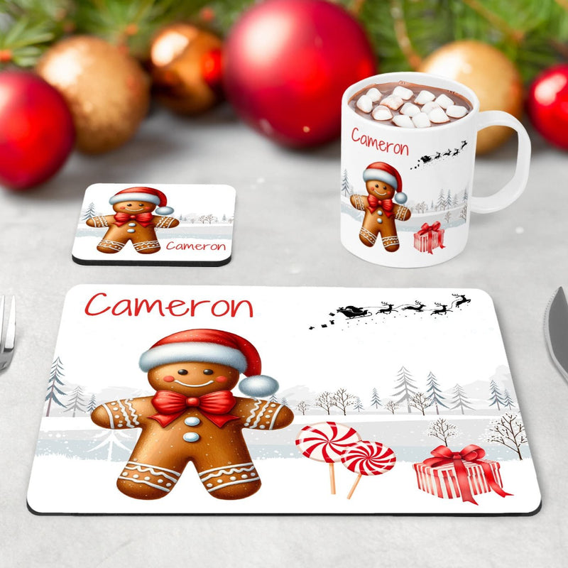 Kids Christmas Table Wear Set. A white mug featuring bright, bold gingerbread man design. Coaster and placemat have similar design on a white background. All personalised with childs name