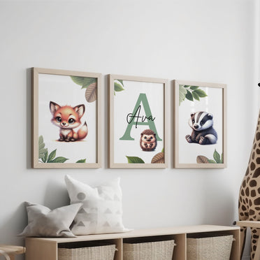 Set of three A4 prints featuring woodland baby animals - fox, badger, and squirrel. The animals are depicted in a cartoony style, resembling coloured pencil drawings. Woodland leaves decorate the edges of the prints. The middle print features a smaller animal than the others, with a large initial letter in the background. A personalised name in black overlays the initial letter.