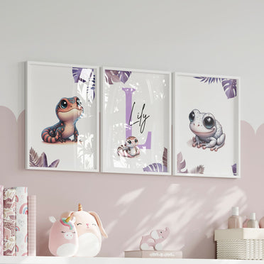 Set of three A4 prints featuring pink/purple reptiles/amphibians - frog, lizard, and snake. The animals are depicted in a cartoony, style resembling coloured pencil drawings in warm shades of pink, purple and orange. Jungle-style leaves in shades of purple decorate the edges of the prints. The middle print features a smaller animal than the others, with a large initial letter in the background. A personalised name in black overlays the initial letter.